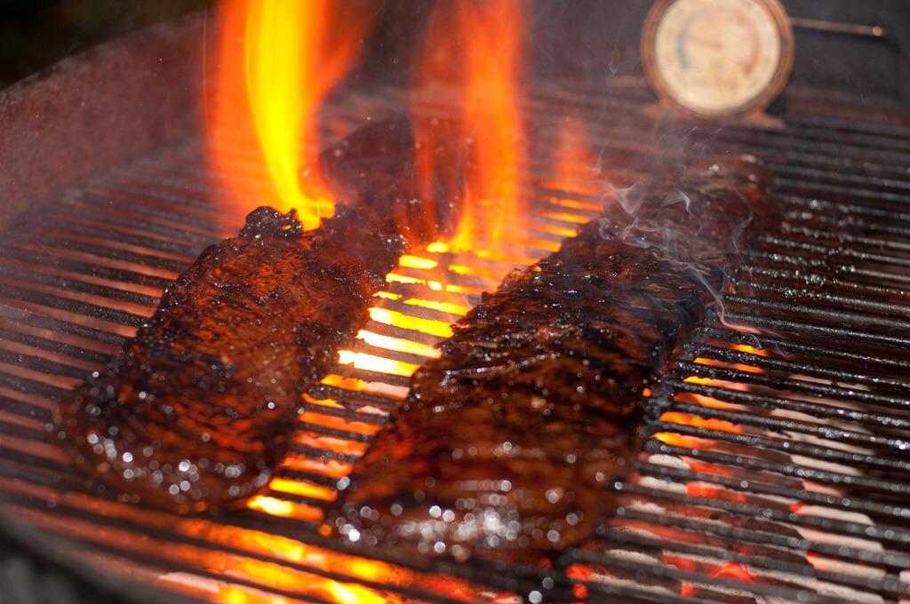 Foto van vlees op een grill met vuur